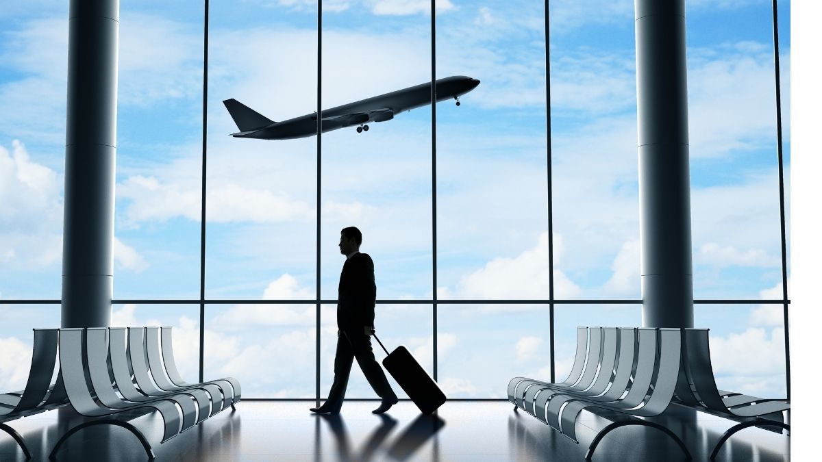 空港ロビーでスーツケースを引くビジネスマン