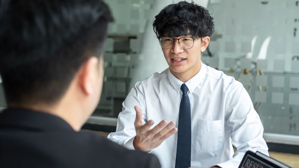 面接で話すメガネのアジア人男性