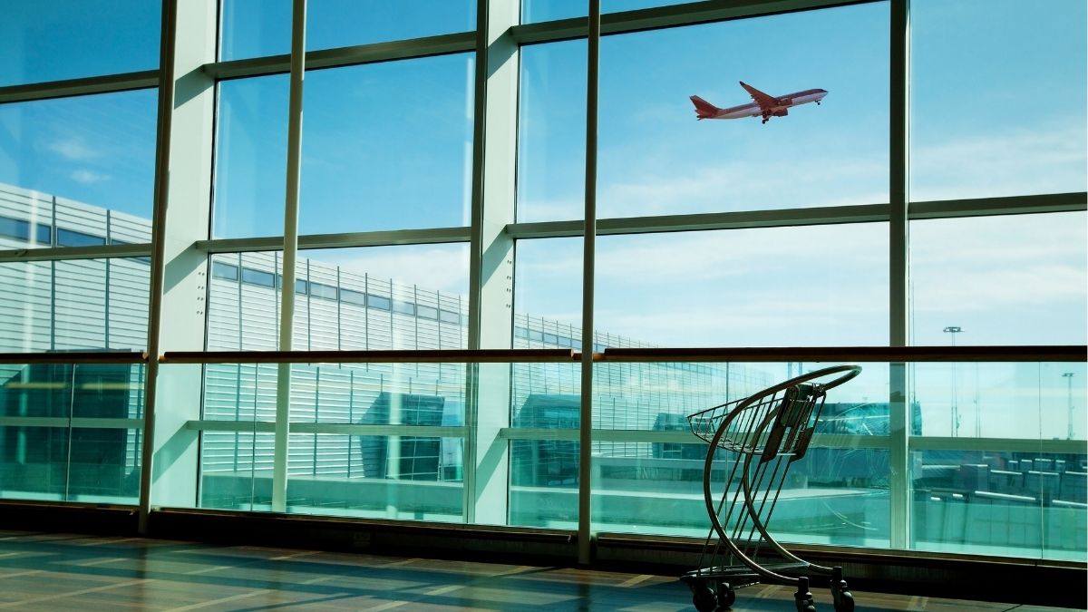 空港の窓越しに飛び立つ飛行機