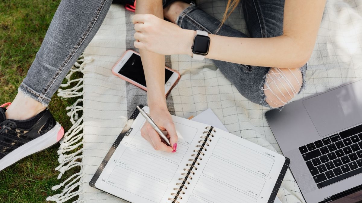 公園でノートとPCを使う女性