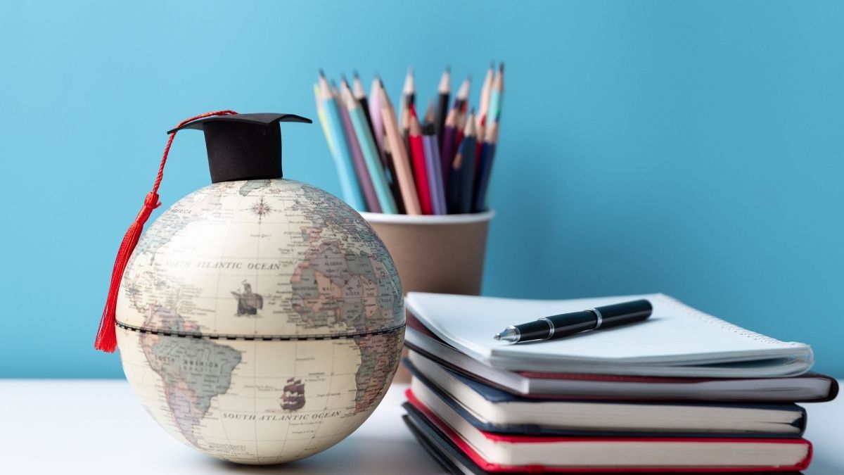 学位帽をかぶった地球儀と本
