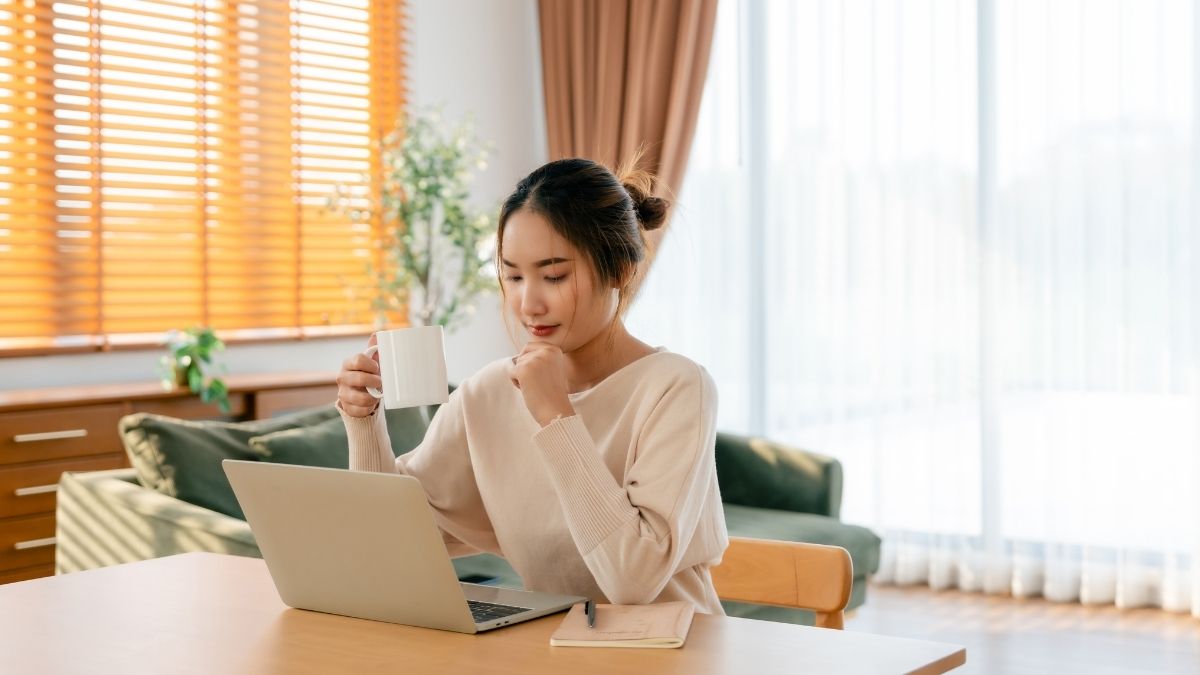 コーヒーを片手にPC作業する女性