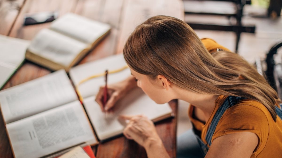 木のテーブルで本を読み勉強する女性